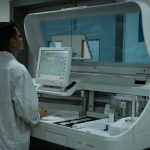 Técnico de laboratório opera um analisador clínico em um laboratório moderno.
