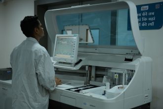 Técnico de laboratório opera um analisador clínico em um laboratório moderno.