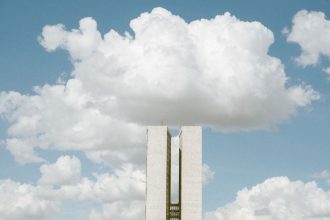 Vista externa do Congresso Nacional, em Brasília, sob um céu parcialmente nublado.